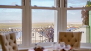 Comedor con una mesa preparada para dos, amplias ventanas que ofrecen vistas a un paisaje lejano.