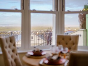 Ein Essbereich mit Tisch für zwei Personen, große Fenster mit Blick auf eine entfernte Landschaft.