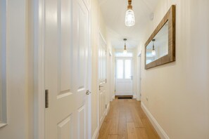 A hallway with white doors, a wooden floor, and a hanging light fixture. - 2 Bed in Bideford (oc-77590) (Northam)