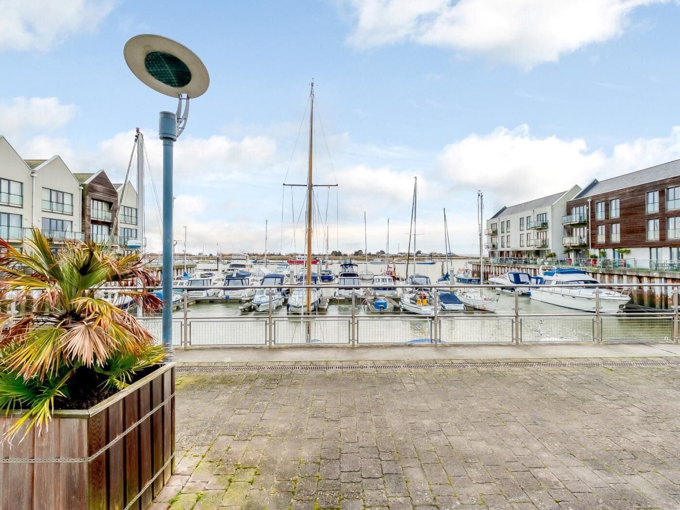 Un port de plaisance avec des bateaux amarrés, un lampadaire et des bâtiments en arrière-plan.