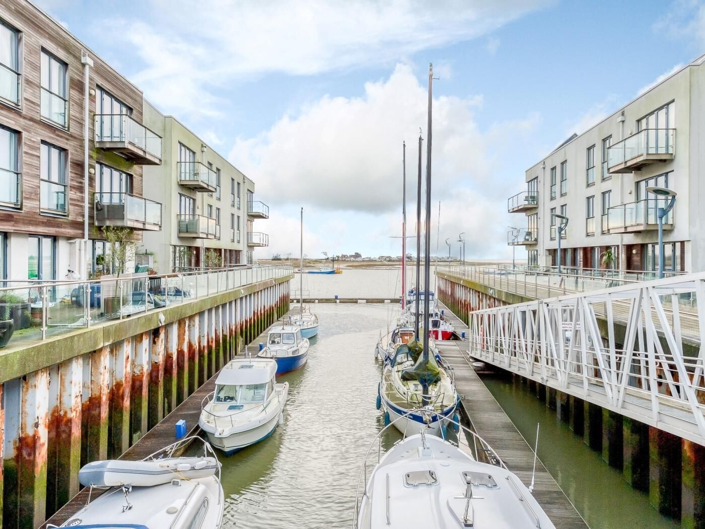 Un port de plaisance avec des bateaux amarrés, un pont et des bâtiments dotés de balcons.