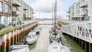 Puerto deportivo con barcos amarrados, un puente y edificios con balcones.