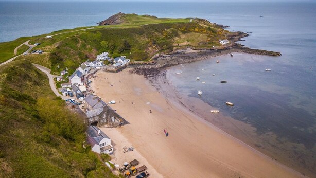 An aerial view of a coastal town with a sandy beach, a small harbor with boats, and houses along the coastline. - 1 Bed in Caernarfon (oc-77891) (Llanaelhaearn)