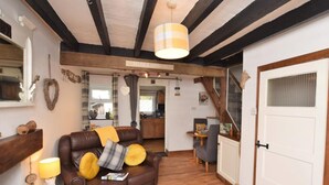 A cozy living room with a brown leather sofa, a wooden coffee table, a lamp, and a fireplace. - 1 Bed in Caernarfon (oc-77891) (Llanaelhaearn)