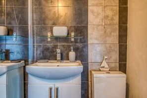 A bathroom with two sinks, a mirror, a shelf with toiletries, and a small decorative boat. - 1 Bed in Caernarfon (oc-77891) (Llanaelhaearn)