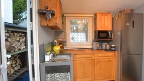 A compact kitchen with a microwave, refrigerator, and wooden cabinets. - 1 Bed in Caernarfon (oc-77891) (Llanaelhaearn)