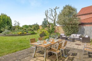 A patio with a table set for dining, surrounded by outdoor furniture. - 4 Bed in Melton Constable (oc-77924) (Briston)