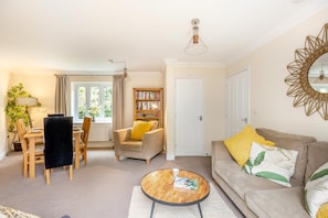 A living room with a sofa, a coffee table, a bookshelf, a dining table with chairs, and a window with curtains. - 3 Bed in Bampton (oc-77931) (Bampton)