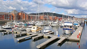 Un port de plaisance avec des bateaux amarrés, des quais en bois et, au fond, des bâtiments rouges.