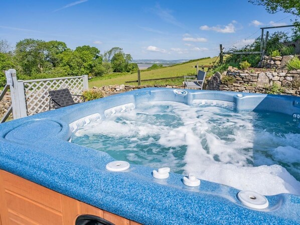 Un jacuzzi con una pared de piedra y vistas al campo.