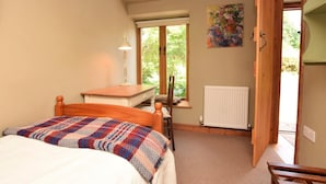 A bedroom with a bed, a desk, a chair, a radiator, a window, and a painting.