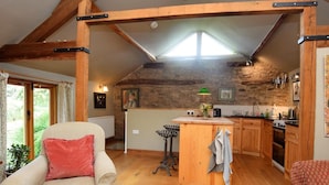 A cozy kitchen with wooden beams, a central island, and a dining area with a chair.