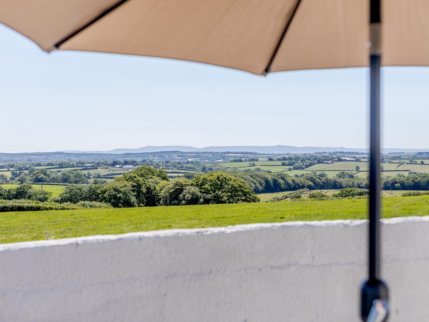 A balcony with a view of a green landscape and distant hills.