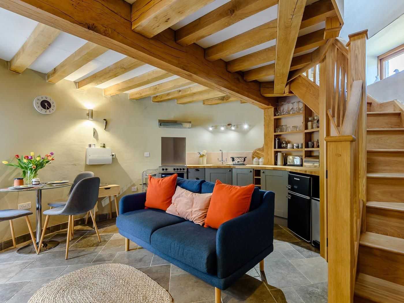 A cozy living area with a sofa, a dining table, and a kitchen in the background.