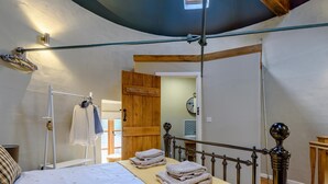 Une chambre à coucher avec un lit à baldaquin, une porte en bois et une petite fenêtre.
