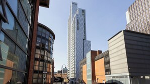 Una moderna strada cittadina con edifici alti, tra cui una torre imponente con una facciata particolare.