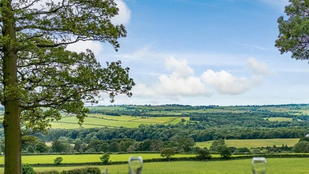A table with two wine glasses and bowls, set against a backdrop of rolling green hills and a clear sky. - 1 Bed in Crook (oc-78487) (North Bitchburn)