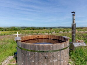 A wooden hot tub surrounded by a chain-link fence, with a metal structure and a cross in the background. - 1 Bed in Penzance (oc-78517) (Newlyn)
