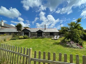 A stone building with a grassy yard, a wooden fence, and a clear sky. - 1 Bed in Penzance (oc-78517) (Newlyn)