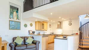 A modern kitchen with wooden cabinets, a central island, and a dining area with a leather sofa. - 2 Bed in Inverness (oc-78537) (Drumnadrochit)