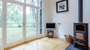 A room with a large sliding glass door, a television on a small table, a fireplace, and a framed picture on the wall. - 2 Bed in Inverness (oc-78537) (Drumnadrochit)