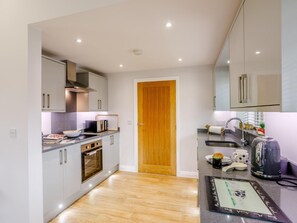 A modern kitchen with grey cabinets, a wooden door, and a countertop with a kettle and mugs. - 2 Bed in Derby (oc-78582) (Stanton by Bridge)