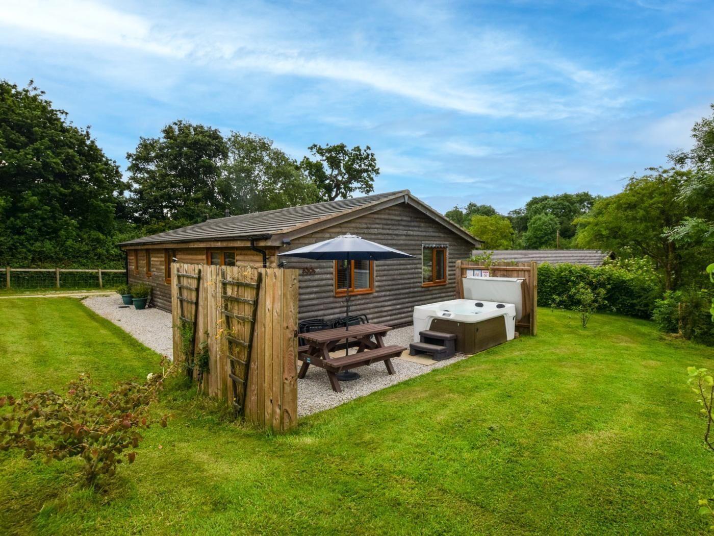Une cabane en rondins avec un patio, un jacuzzi et une table de pique-nique.