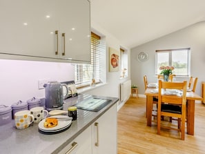 A modern kitchen with a dining area, featuring a kitchen island, wooden chairs, and a dining table.