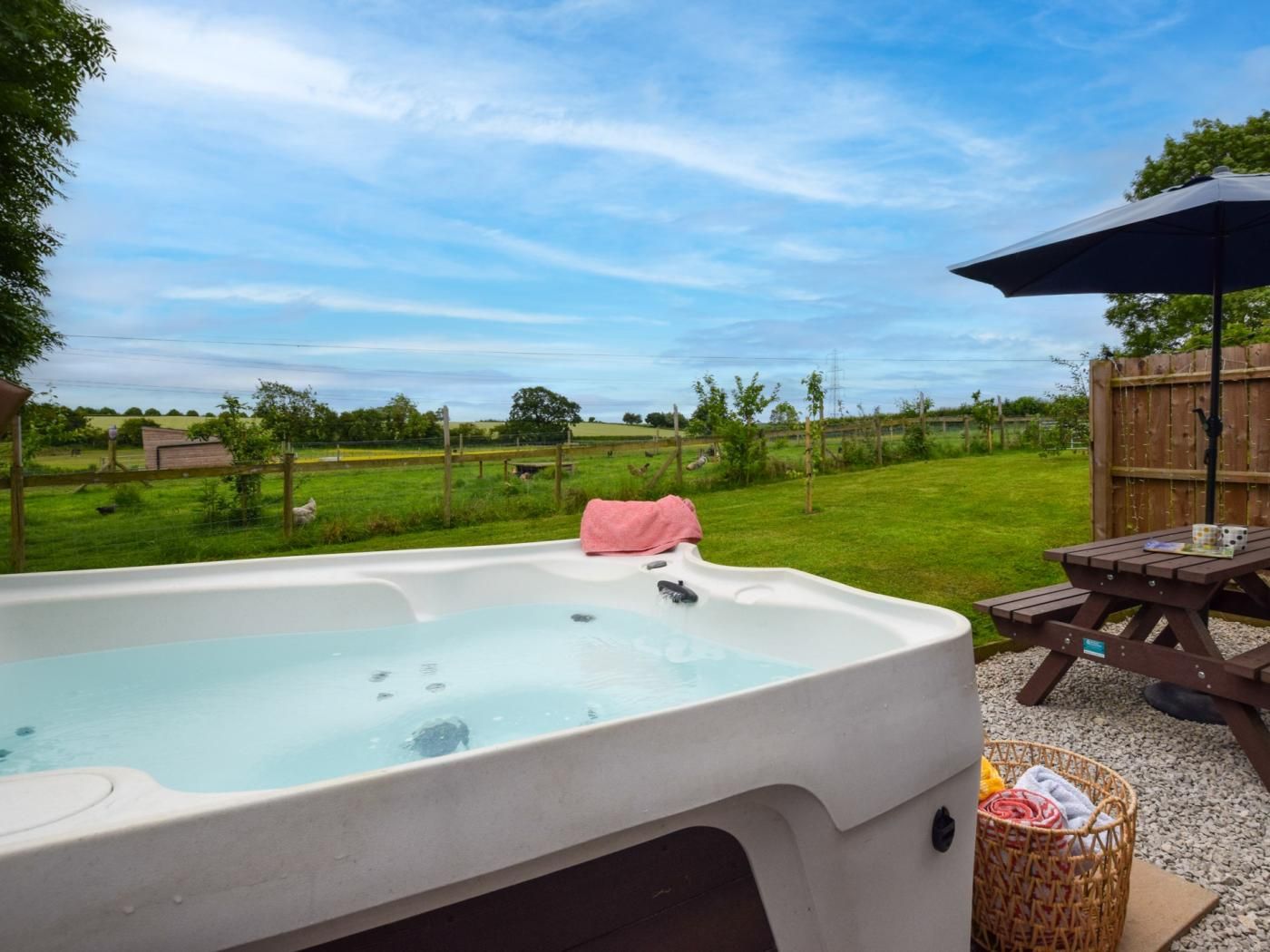 A hot tub with a view of a grassy field and a wooden fence.