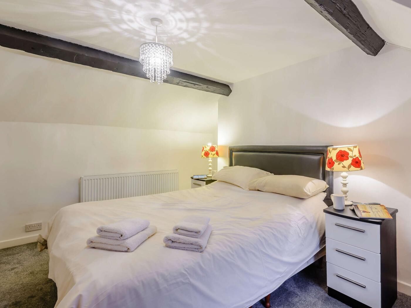 Ein Schlafzimmer mit einem Bett, zwei Nachttischen mit Lampen, einer Heizung und einer Deckenleuchte.