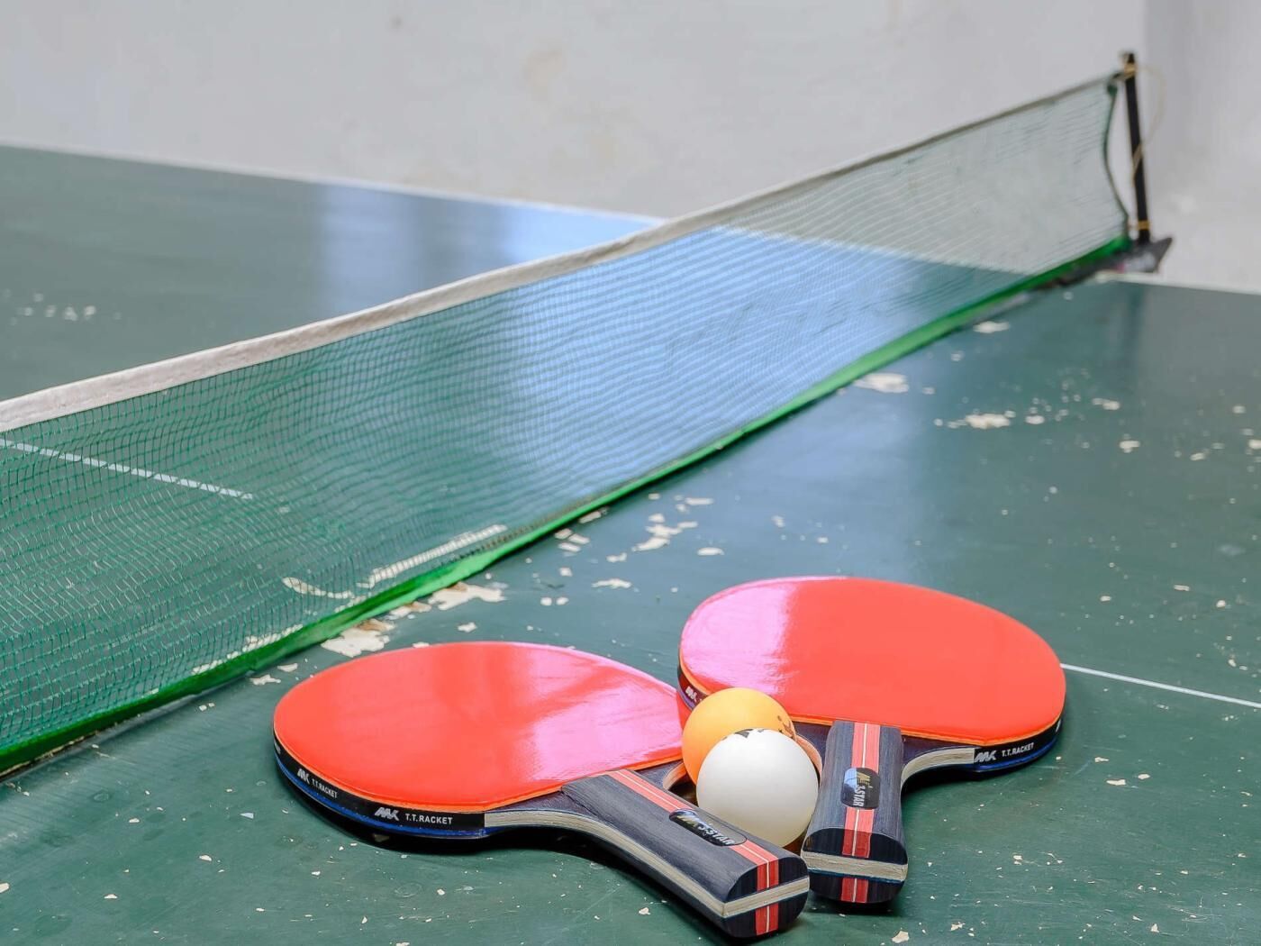 A table tennis table with two red paddles and a ball.