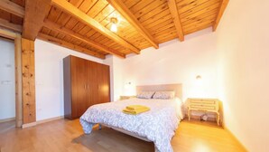 A bedroom with a bed, wooden wardrobe, and bedside tables. - ANCLA Country House: Ideal for families, with a barbecue, outdoor space, and a game room (Barca)