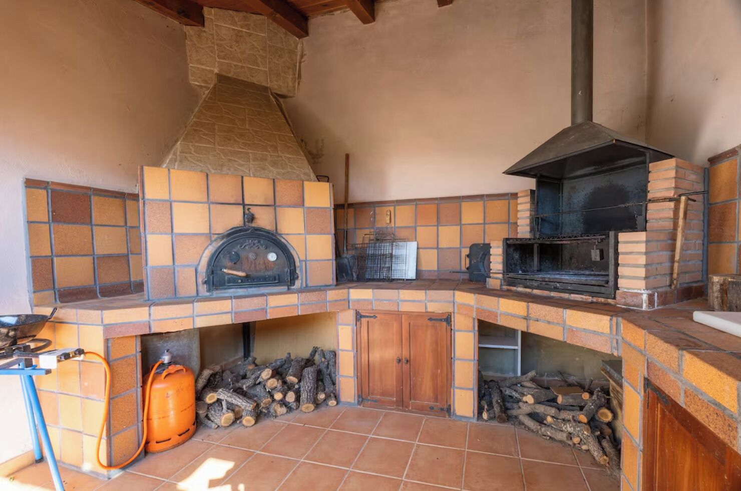 Una cocina con chimenea de piedra, horno de leña y salpicadero de azulejos.