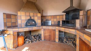 A kitchen with a stone chimney, a wood-fired oven, and a tiled backsplash. - ANCLA Country House: Ideal for families, with a barbecue, outdoor space, and a game room (Barca)