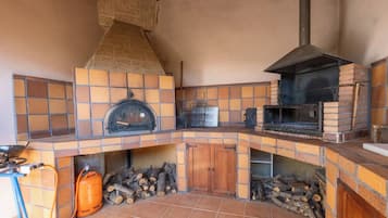 Una cocina con chimenea de piedra, horno de leña y salpicadero de azulejos.
