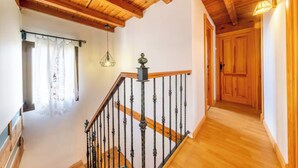 A wooden staircase with a metal railing, a hanging light fixture, and a door leading to another room. - ANCLA Country House: Ideal for families, with a barbecue, outdoor space, and a game room (Barca)