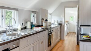 Een moderne keuken met een groot eiland, een ingebouwde oven en uitzicht op de eethoek.