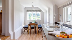 Een moderne keuken met een eetgedeelte, een groot raam en uitzicht op groen.