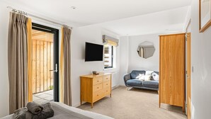Une chambre à coucher comprenant un lit, une commode en bois, un téléviseur, un canapé et une armoire.