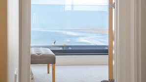 Un balcon avec vue sur la mer, un banc rembourré et un cadre de porte.