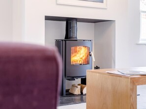 A modern living room with a wood-burning stove, a wooden table, and a framed picture on the wall. - 5 Bed in Market Rasen (oc-78678) (Tealby)