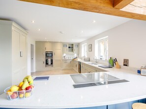 A modern kitchen with white cabinetry, a central island, and a fruit basket. - 5 Bed in Market Rasen (oc-78678) (Tealby)