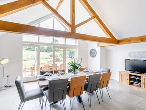 A dining area with a high ceiling, wooden beams, a large window, and a television. - 5 Bed in Market Rasen (oc-78678) (Tealby)