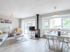 Ein modernes Wohnzimmer mit Kamin, Essbereich und Fernseher.