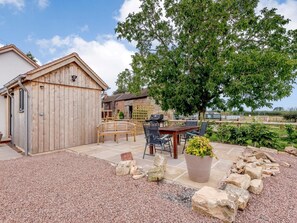 A wooden shed, a patio with a table and chairs, a barbecue grill, and a large tree. - 2 Bed in Newent (oc-78696) (Clifford's Mesne)