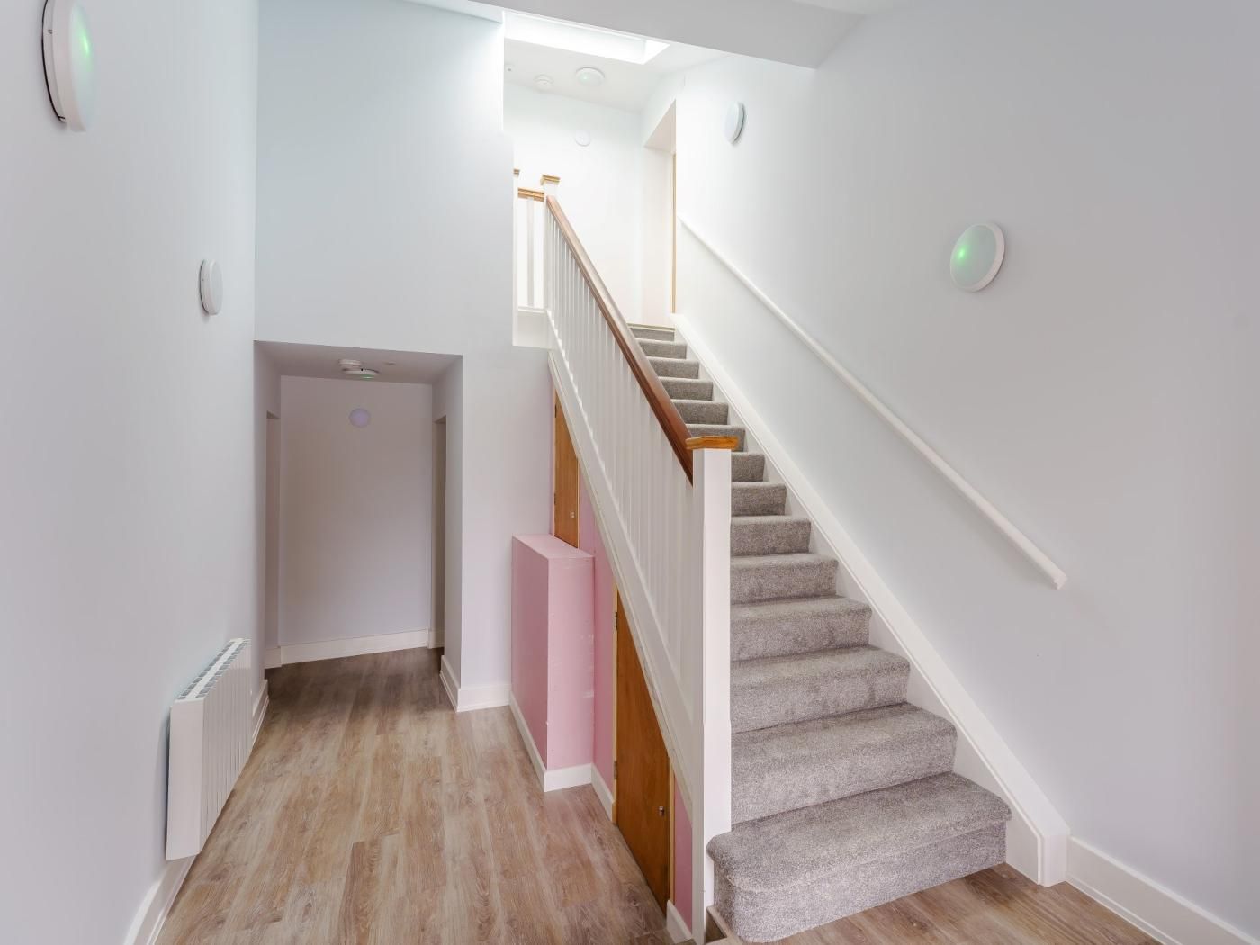Una escalera con peldaños alfombrados y barandillas de madera, que conduce a un piso superior.