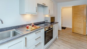 Eine moderne Küche mit weißen Schränken, einem eingebauten Backofen und einer Mikrowelle.