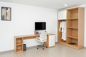 A modern room with a wooden desk, a white chair, a TV, and a wardrobe with hanging clothes. - Shankee Hotel Saigon Bui Vien Street (Ho Chi Minh City)