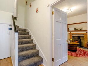 Eine Treppe führt zu einem Raum mit Kamin, einer Tür und einem kleinen Tisch mit einer Vase.