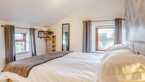 Een slaapkamer met een bed, een raam, een spiegel en uitzicht op het omliggende landschap.